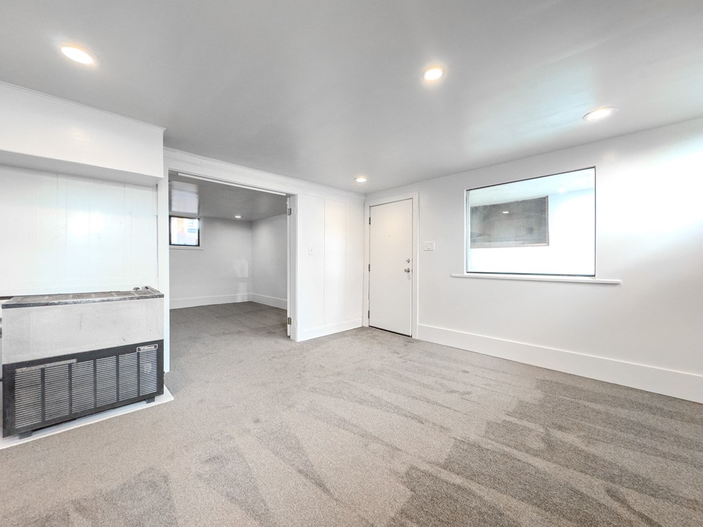 a living room with white walls and a fireplace and a window