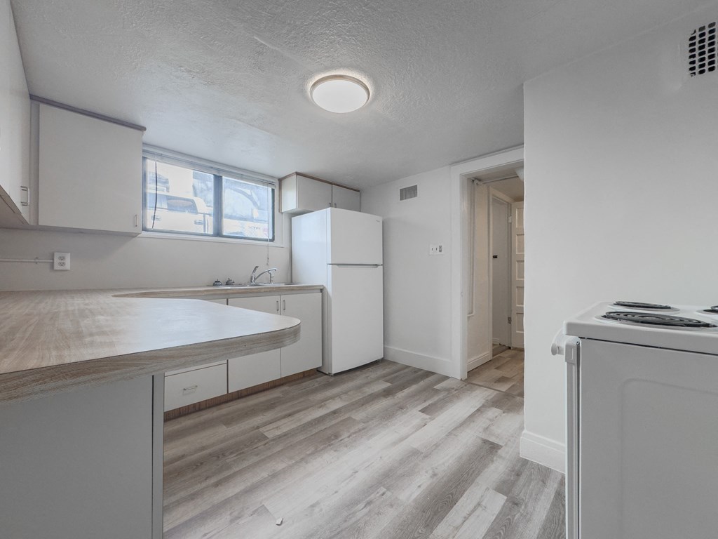 an empty kitchen with white cabinets and a white stove and refrigerator