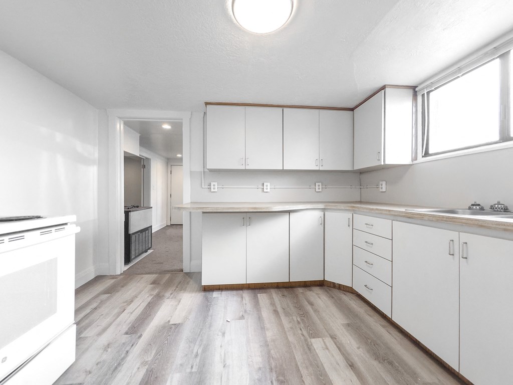 an empty kitchen with white cabinets and a wood floor