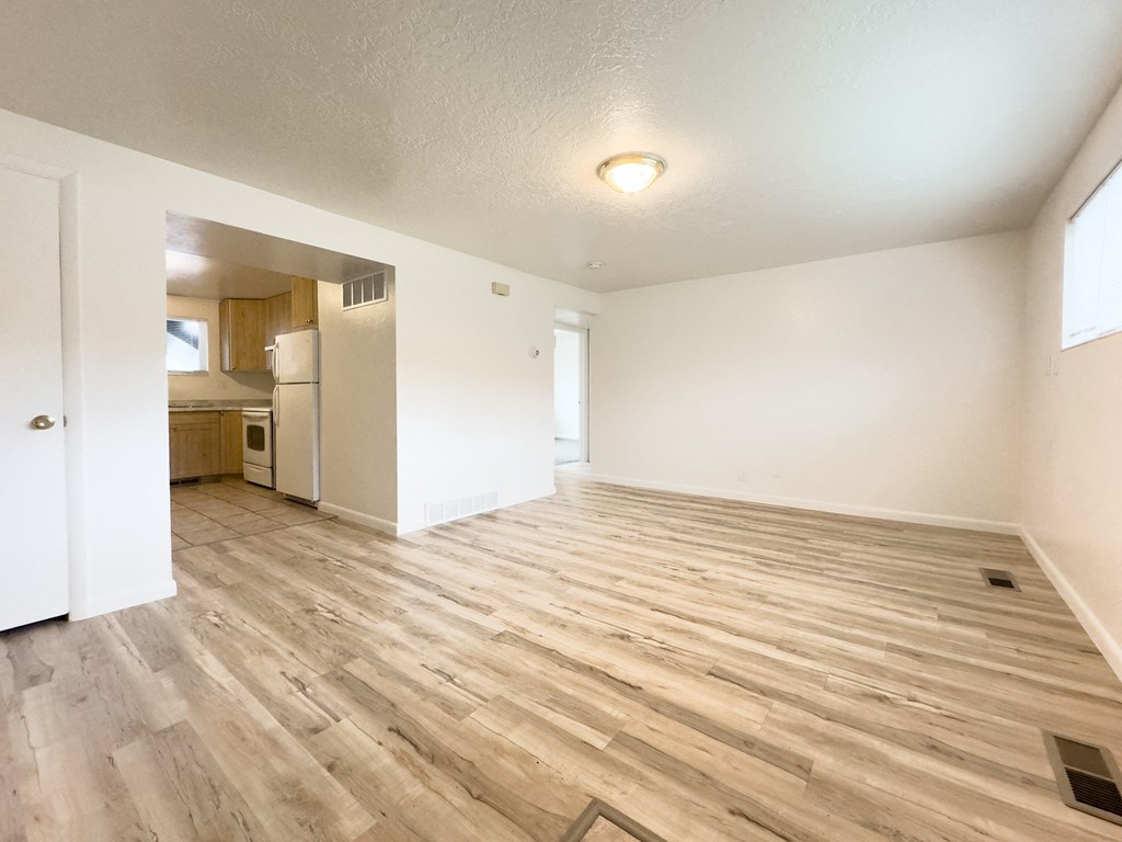 the living room and kitchen of an apartment with wood flooring