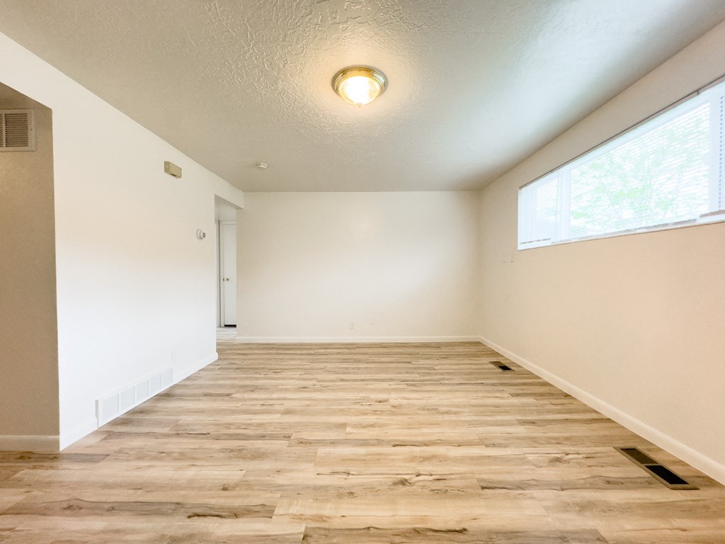 an empty living room with wood flooring and a large window
