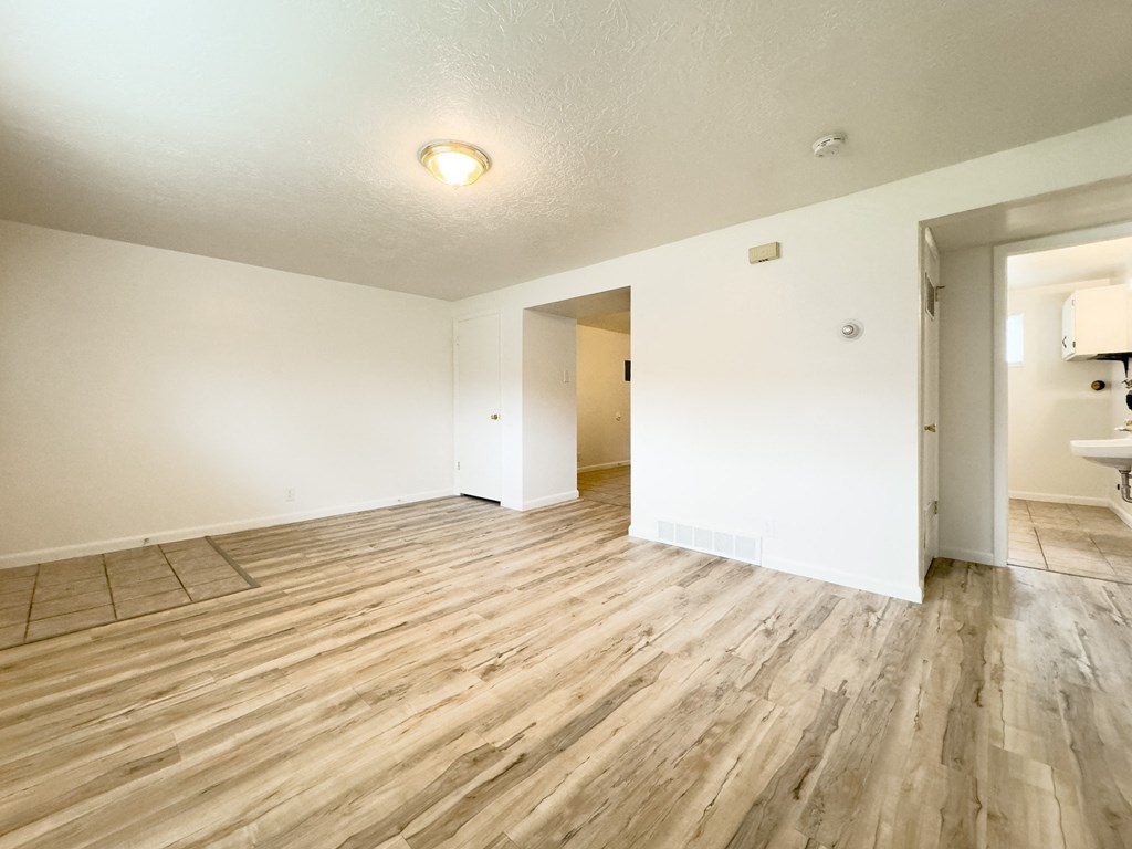the living room and dining room of an apartment with wood flooring