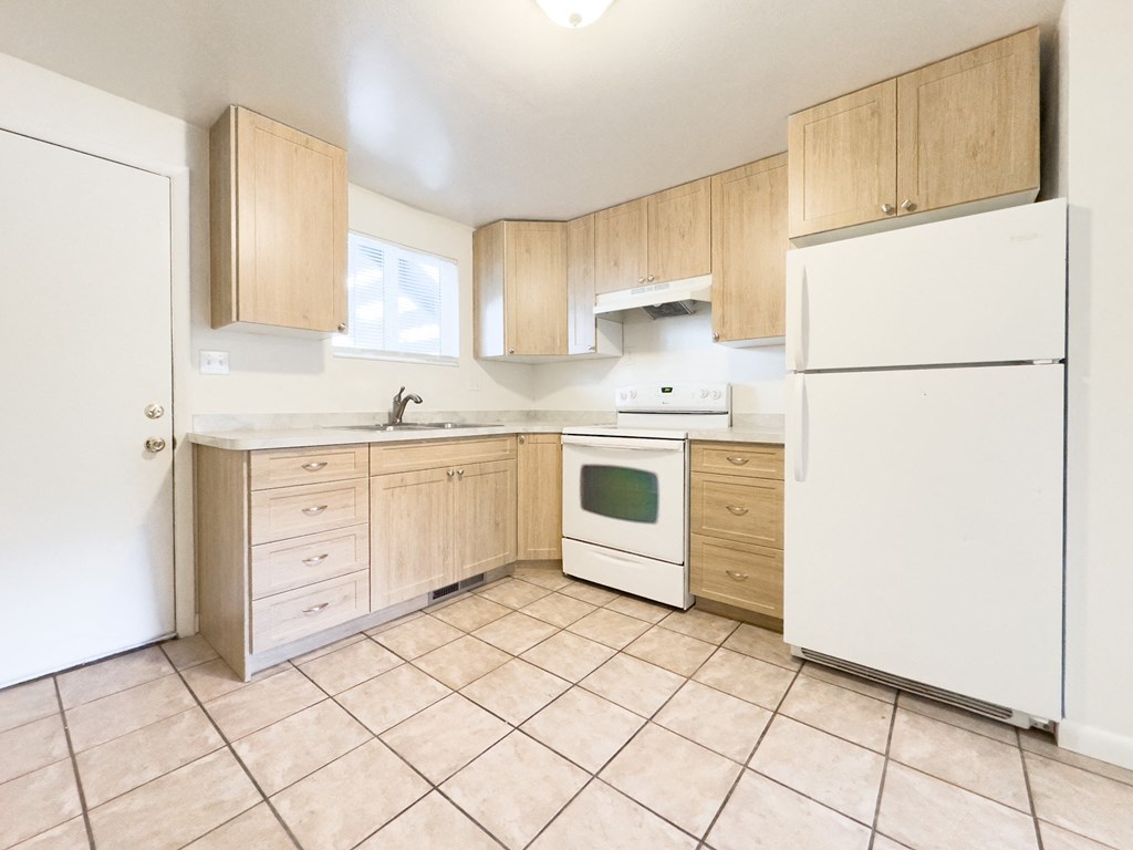 an empty kitchen with white appliances and wooden cabinets