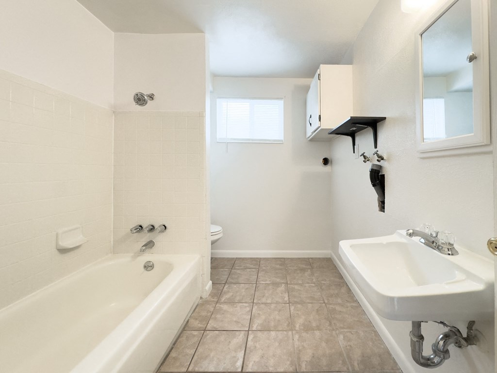 a white bathroom with a tub and a sink and a mirror
