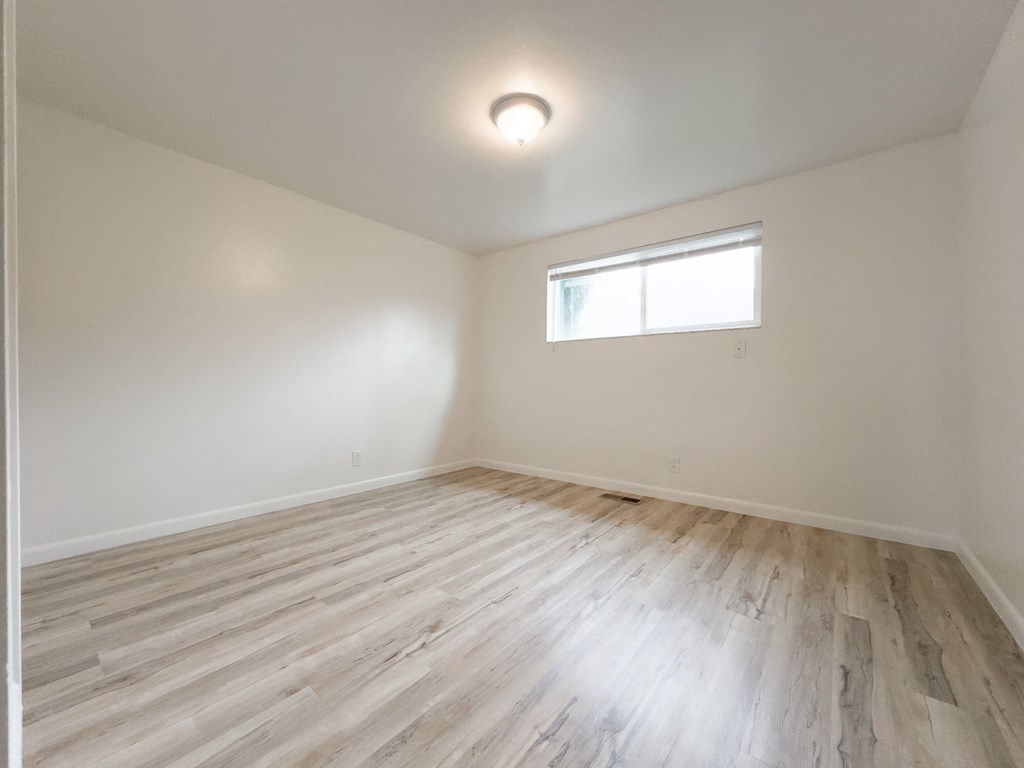 an empty room with wood floors and a window