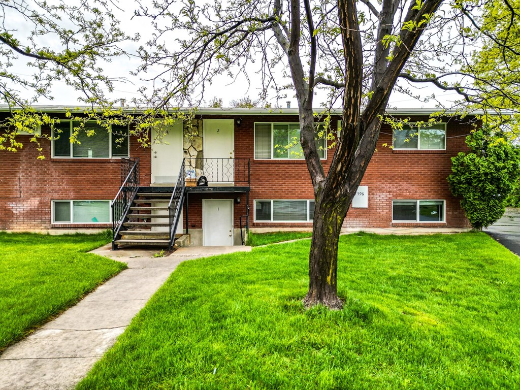 front view of a red brick building with a tree in the yard