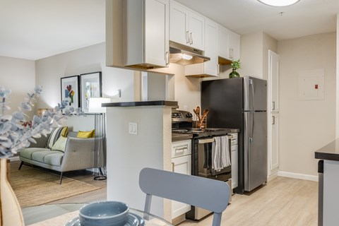 A modern kitchen with a black refrigerator and a grey chair.