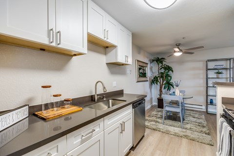 A modern kitchen with white cabinets and a wooden cutting board on the counter.