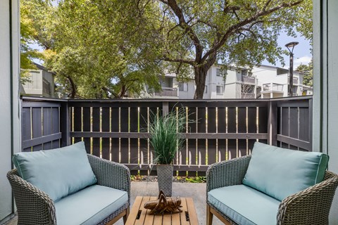 A patio with two chairs and a table with a plant on it.