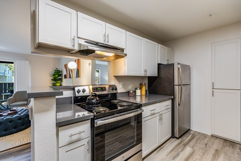 A modern kitchen with white cabinets and stainless steel appliances.
