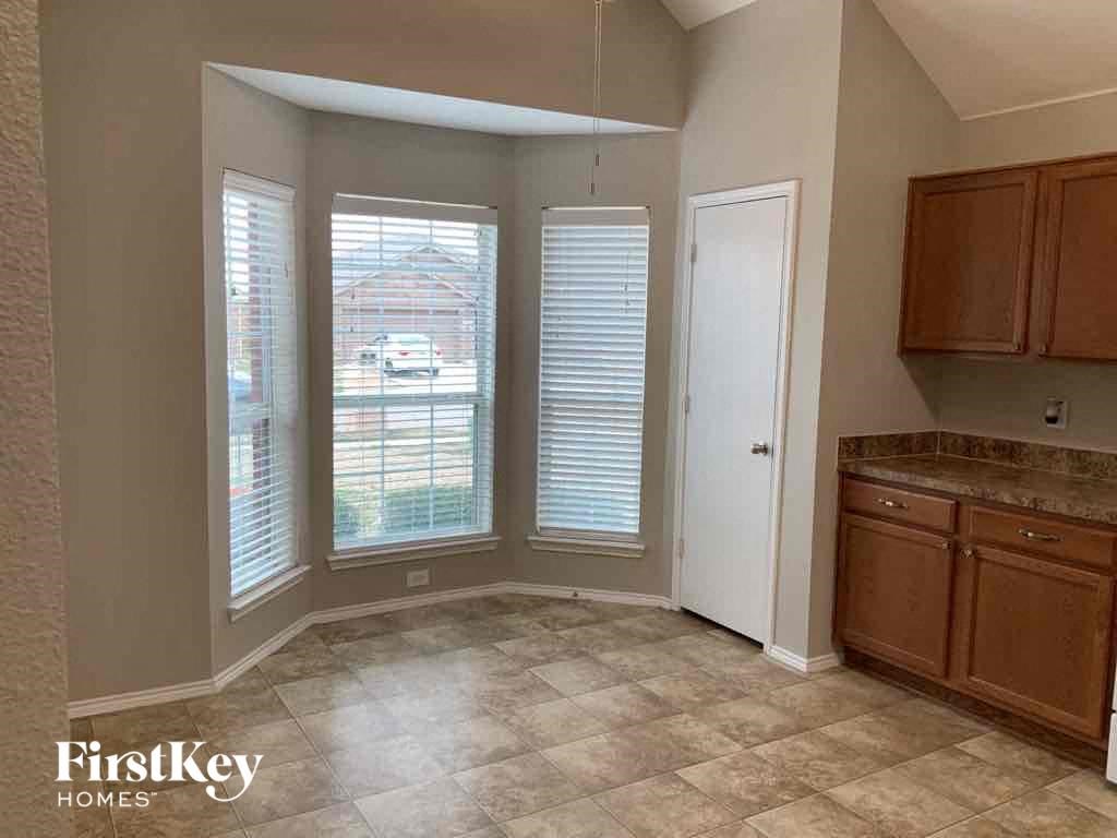 an empty kitchen with three windows and a sink