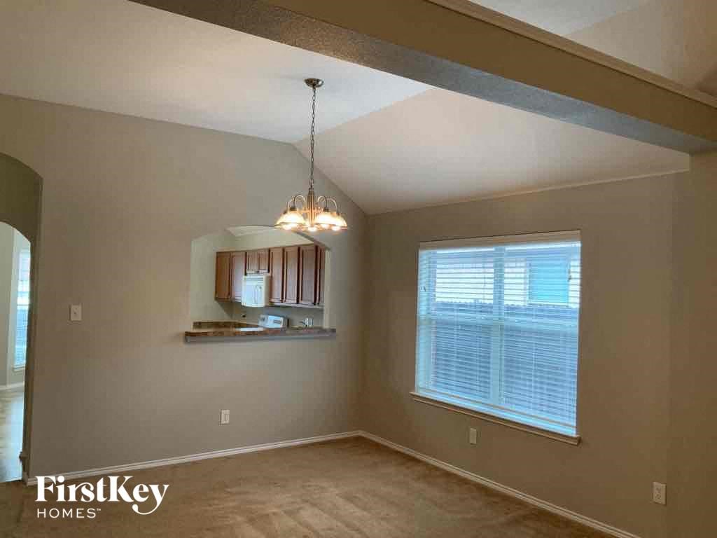 an empty dining room with a window and a chandelier