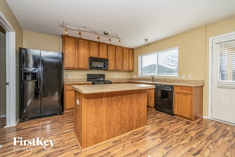 A kitchen with wooden cabinets and a black refrigerator.