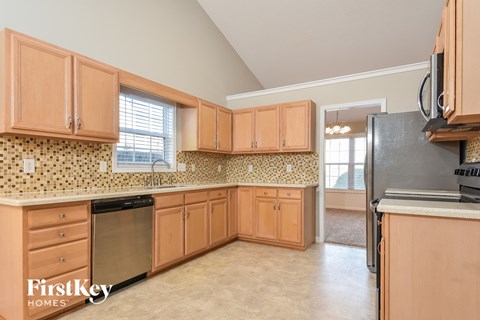 A kitchen with wooden cabinets and a black refrigerator.