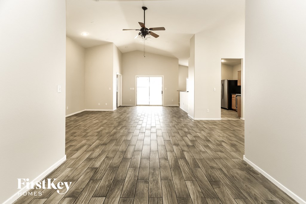 A spacious room with wooden flooring and a ceiling fan.