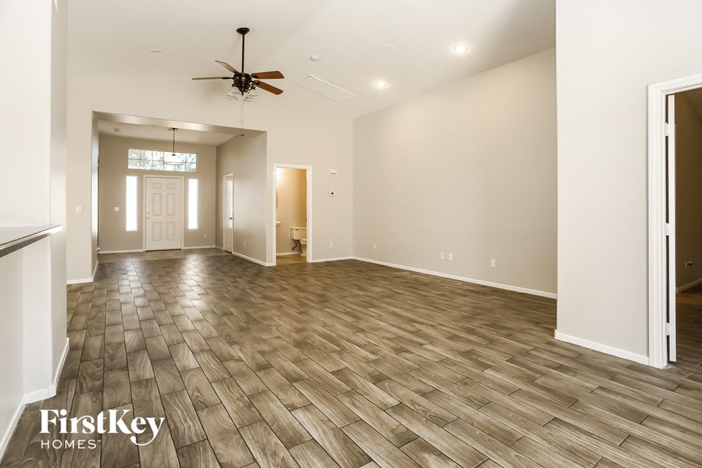 A spacious room with wooden flooring and a ceiling fan.