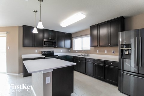 A modern kitchen with black cabinets and stainless steel appliances.