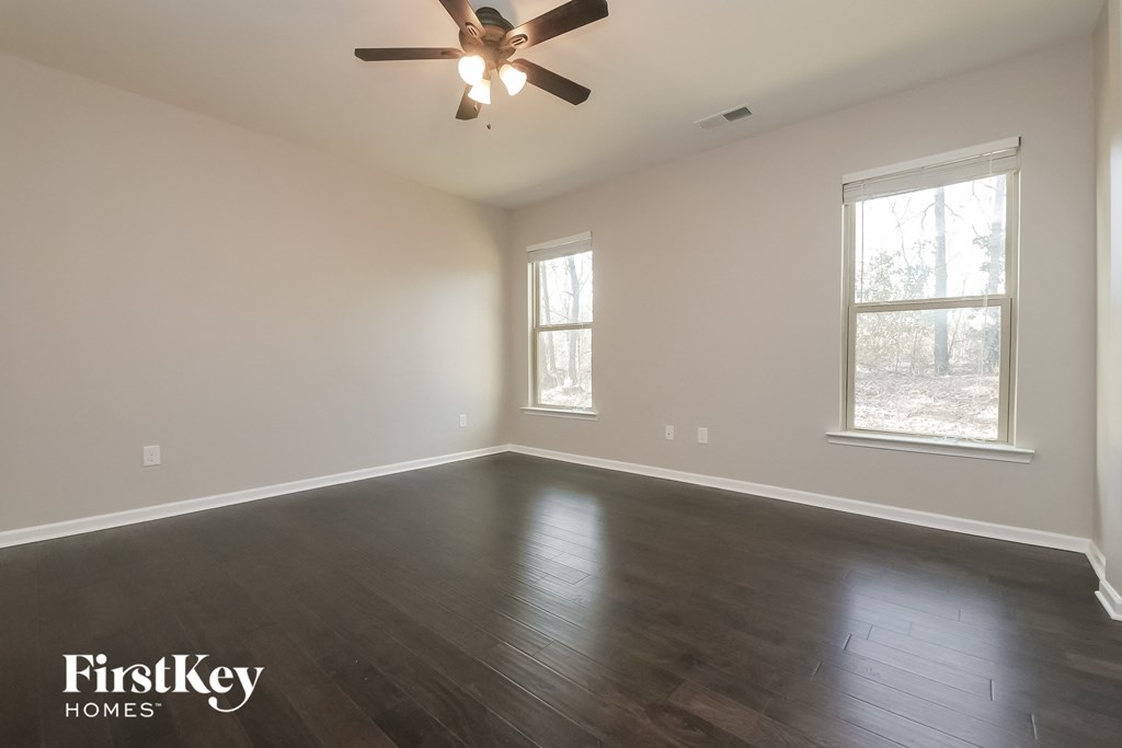 an empty living room with wood floors and a ceiling fan