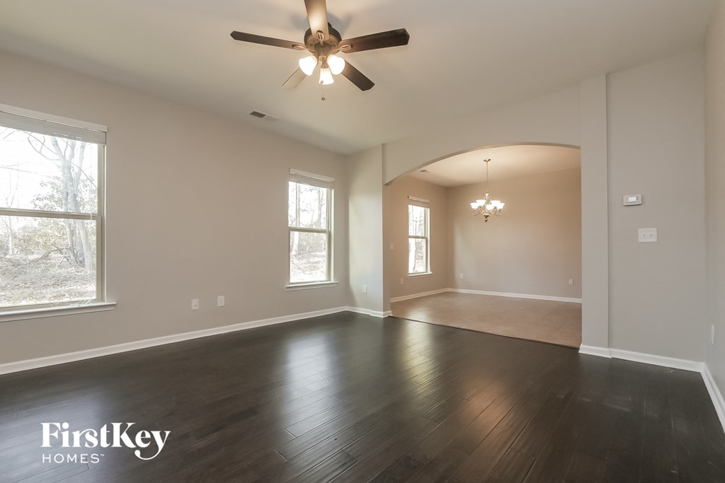 an empty living room with wood floors and a ceiling fan
