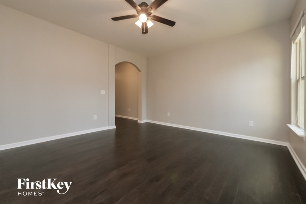 an empty living room with wood floors and a ceiling fan
