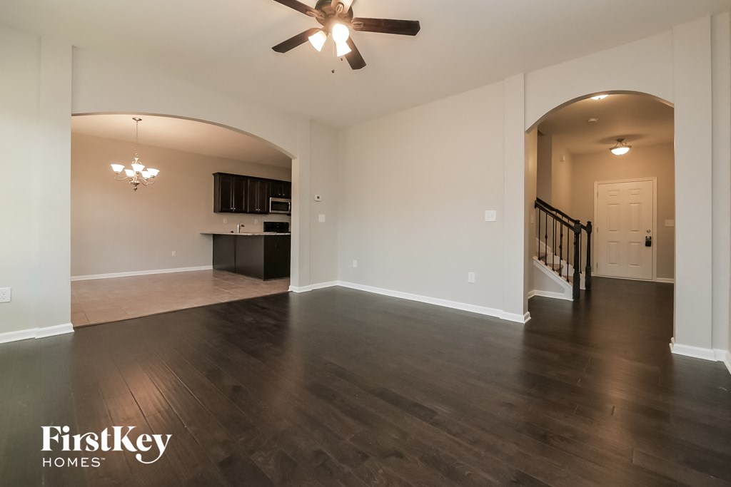 an empty living room with wood floors and a ceiling fan