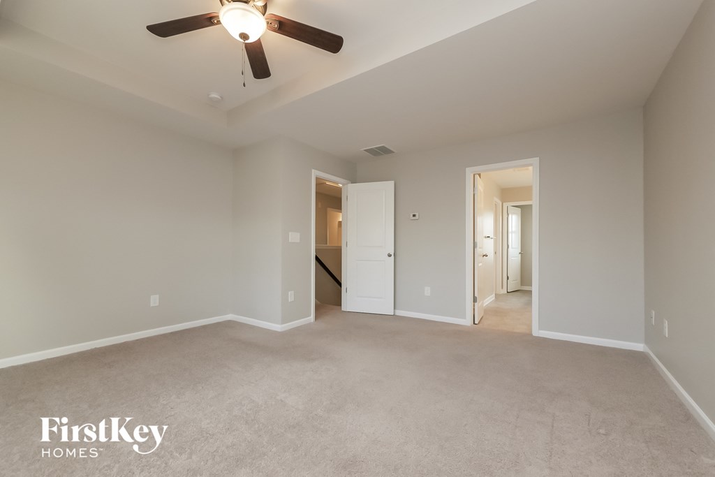 a spacious living room with carpet and a ceiling fan