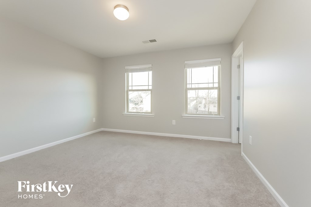a bedroom with a carpeted floor and two windows