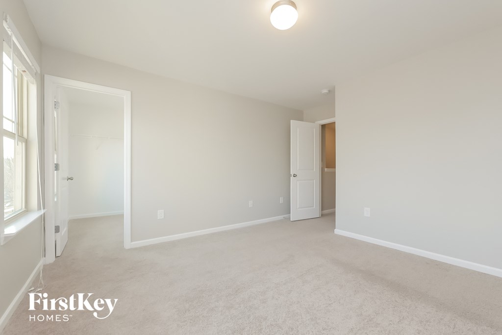 a spacious living room with white carpet and a door to a closet
