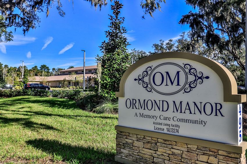a sign for omron manor with a building in the background