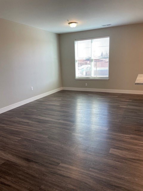 an empty living room with wood floors and a window