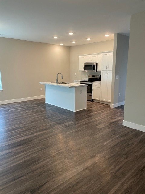 an empty living room with a kitchen with a sink