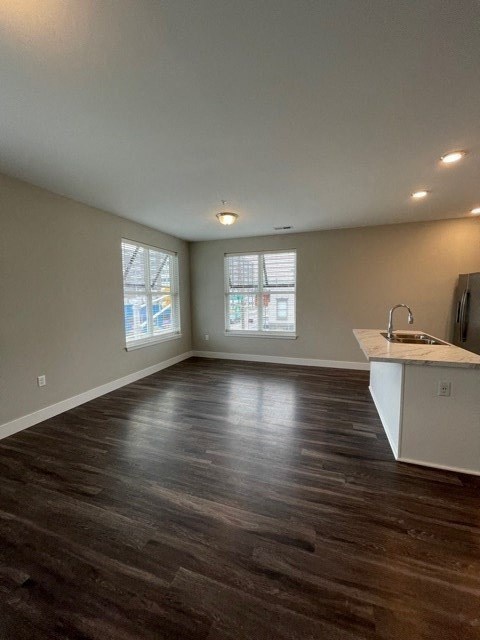 an empty living room with a sink and a kitchen