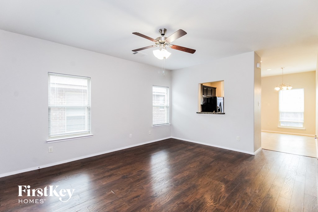an empty living room with wood floors and a ceiling fan