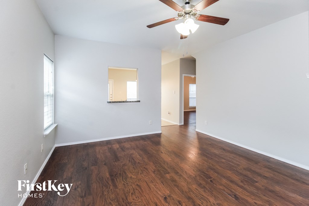 an empty living room with a ceiling fan and wood flooring