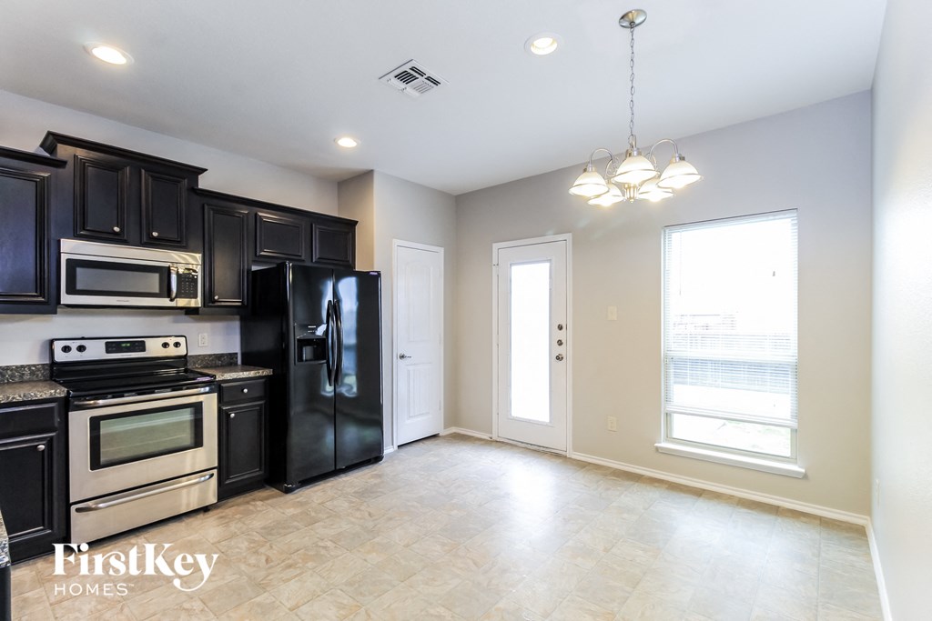 an empty kitchen with black cabinets and stainless steel appliances