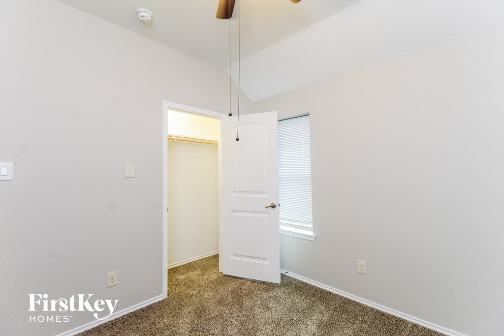 a bedroom with white walls and a door to a closet