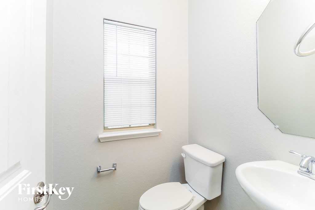 a bathroom with a toilet and a sink and a window