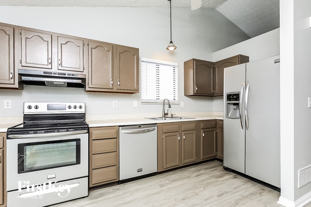 A kitchen with a white refrigerator, brown cabinets, and a stainless steel oven.