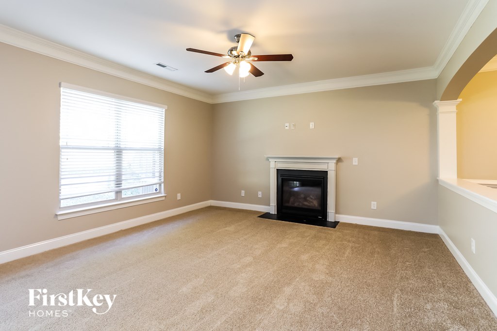 A living room with a fireplace and a ceiling fan.