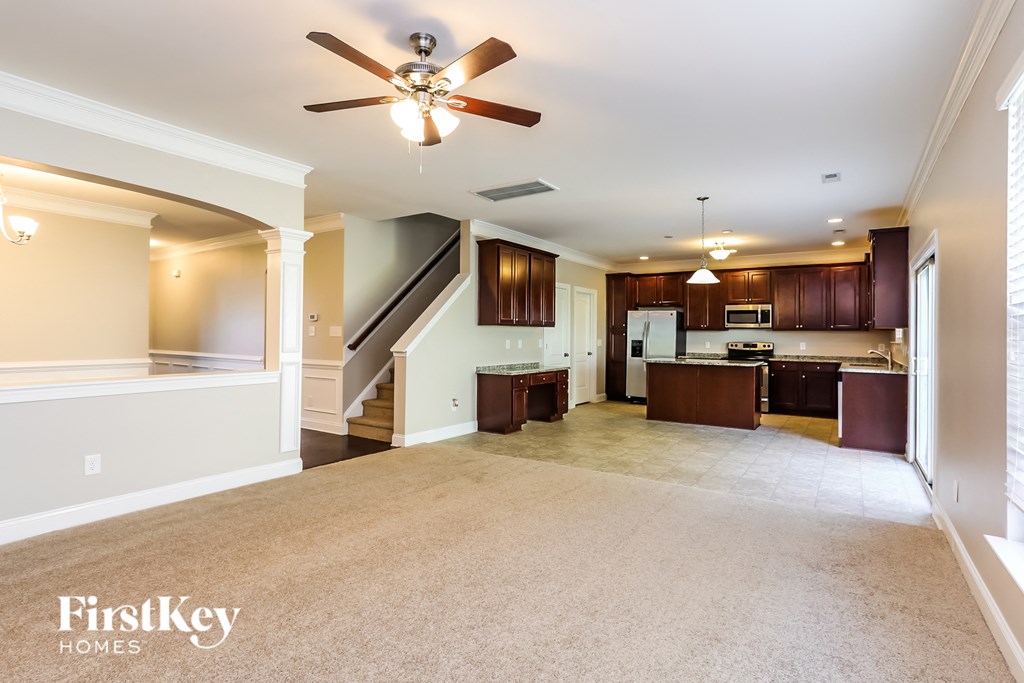 A spacious living room with a carpeted floor and a ceiling fan.