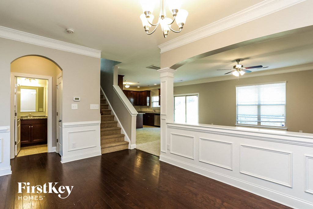 A spacious living room with wood floors and a staircase leading to the upper level.