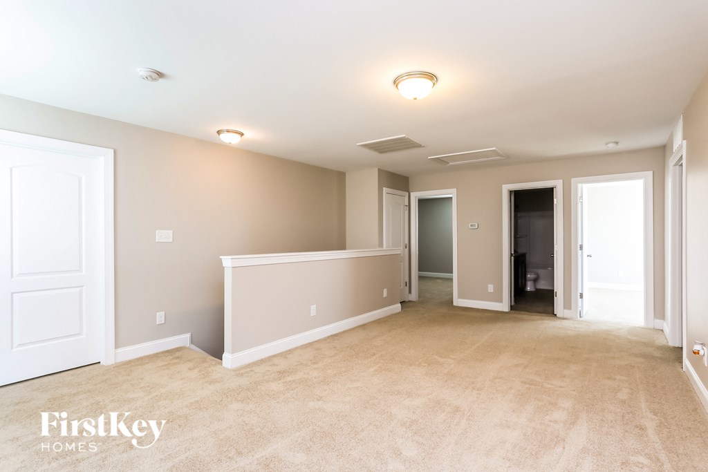 A spacious empty room with a carpeted floor and white walls.