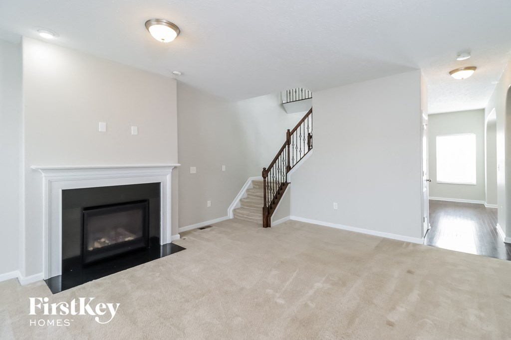 the living room has a fireplace and stairs to the side of it