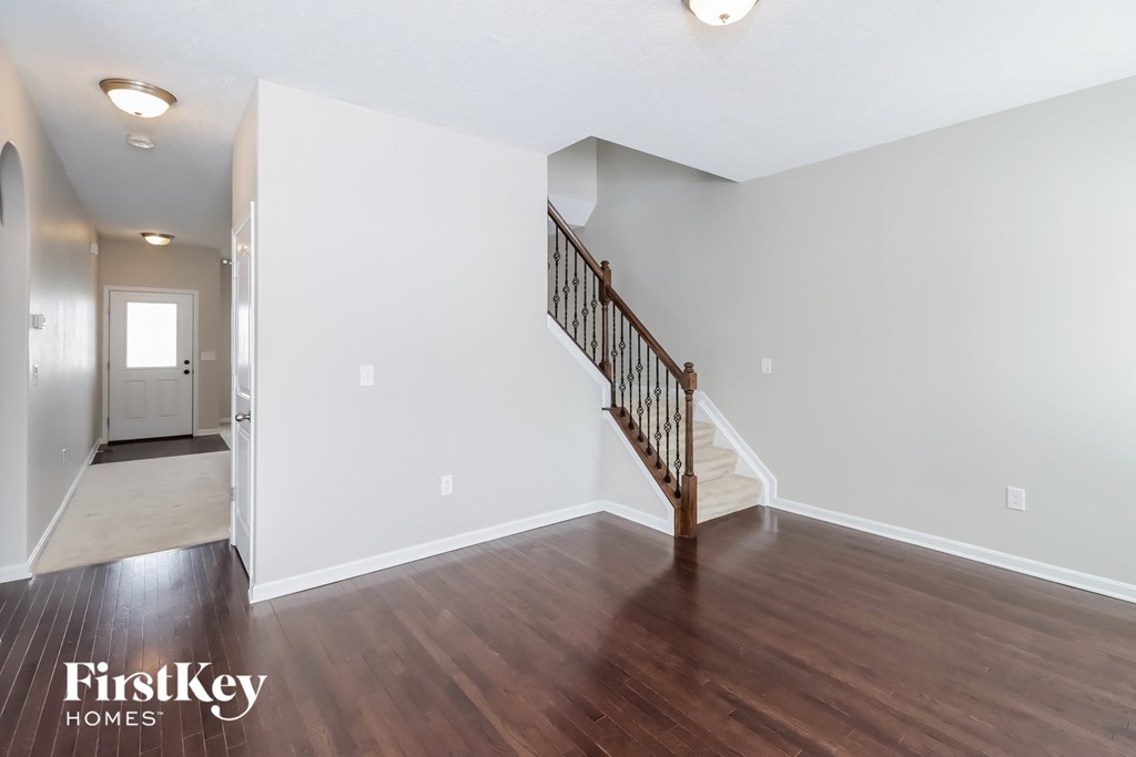 the living room and entryway of an empty house with white walls and wood floors