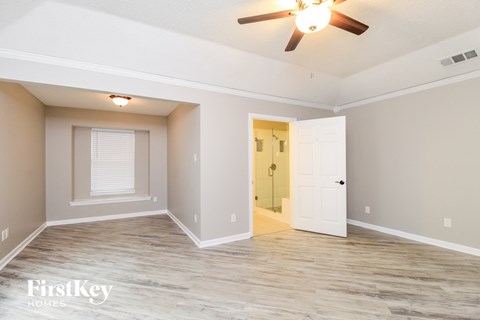 A spacious room with a ceiling fan and a door leading to another room.