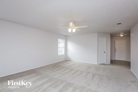 A spacious room with a carpeted floor and a ceiling fan.