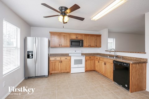 A kitchen with wooden cabinets and a black dishwasher.