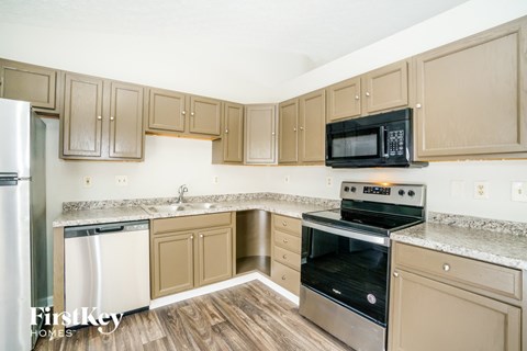 A kitchen with wooden cabinets and a black microwave above the stove.