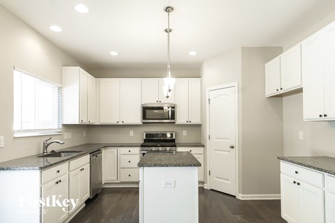 a renovated kitchen with white cabinets and granite counter tops
