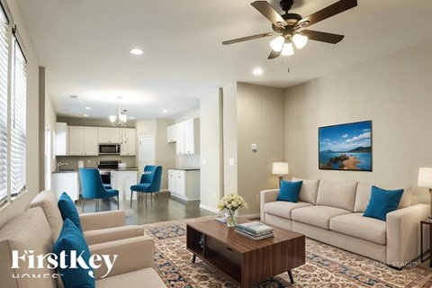 A well-lit living room with a beige sofa, a coffee table, and a painting on the wall.